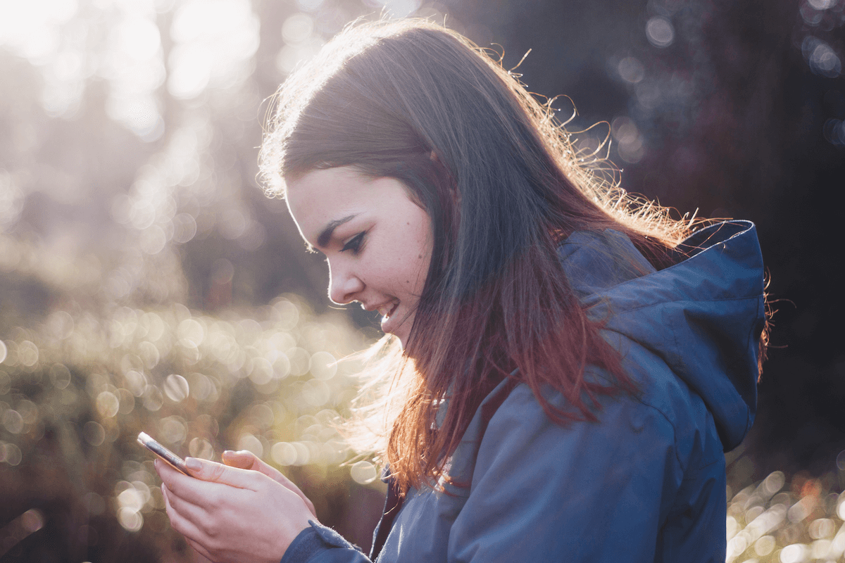 Mineur consultant son smartphone et souriant. 