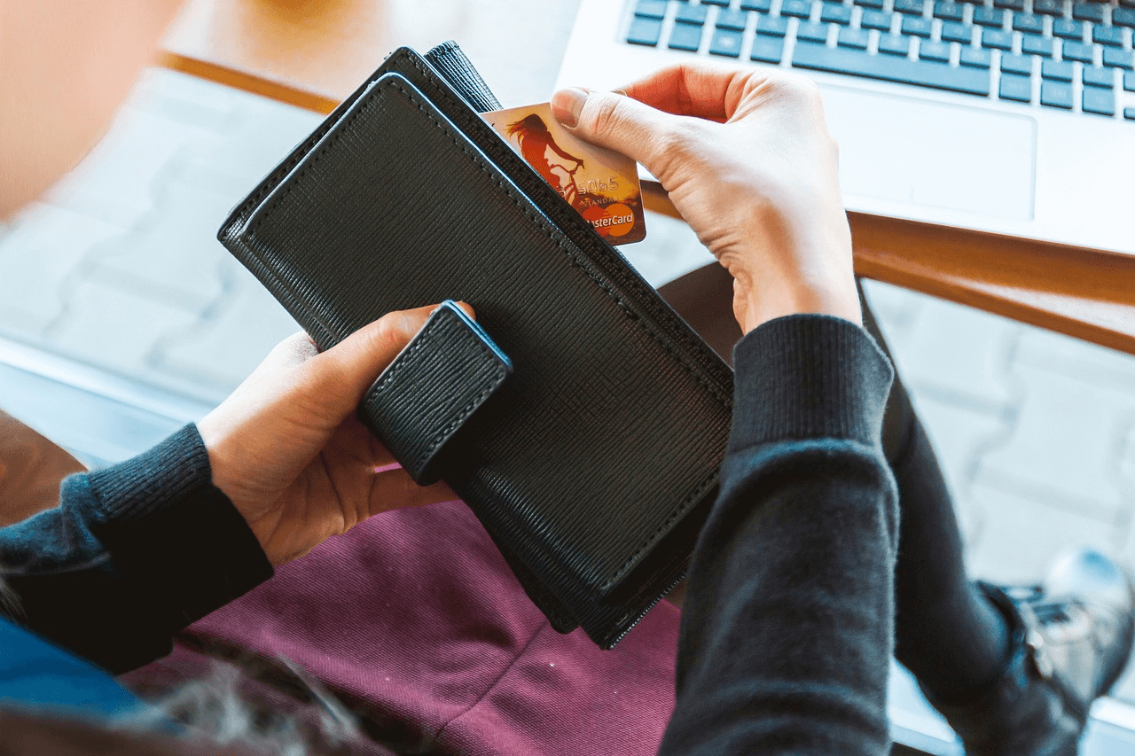 Une jeune femme prenant une carte bancaire parmi ses moyens de paiement.