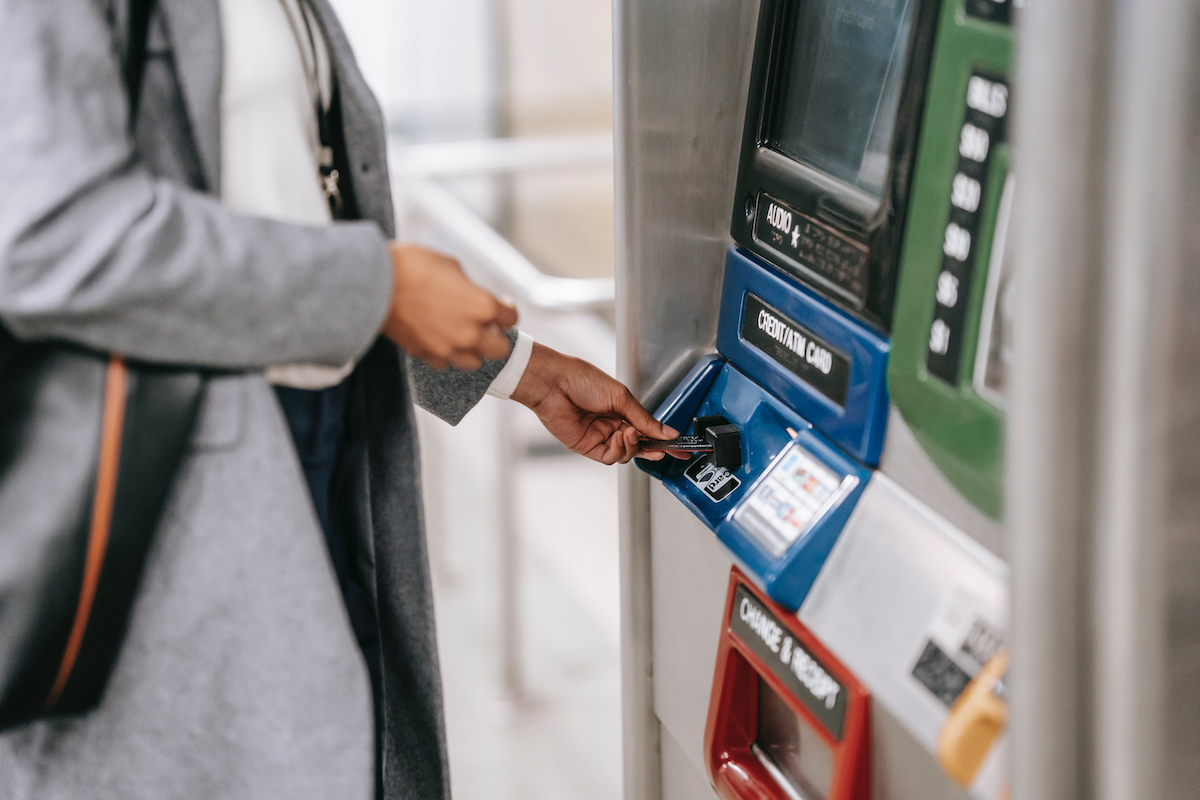 Une jeune femme réalisant un retrait au distributeur de sa banque. 